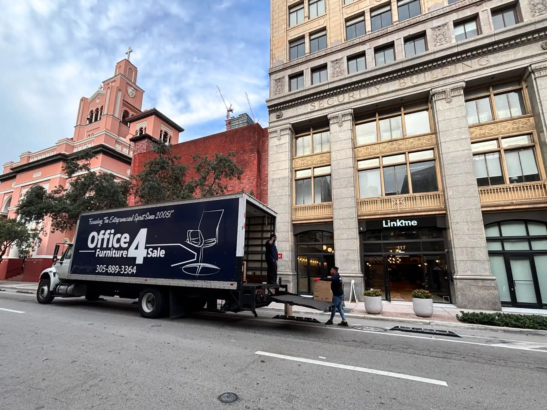 The OF4S delivery box truck parked on a city street outside the building on delivery day