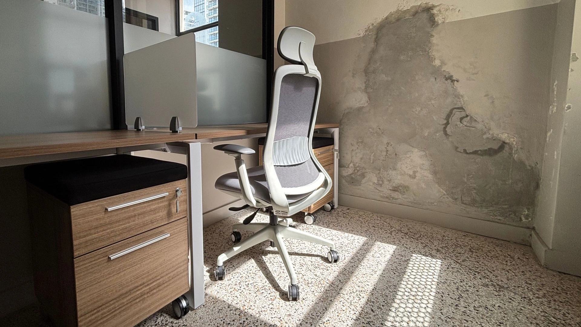 Private office with a wood desk, a white mesh task chair and an exposed plaster accent wall