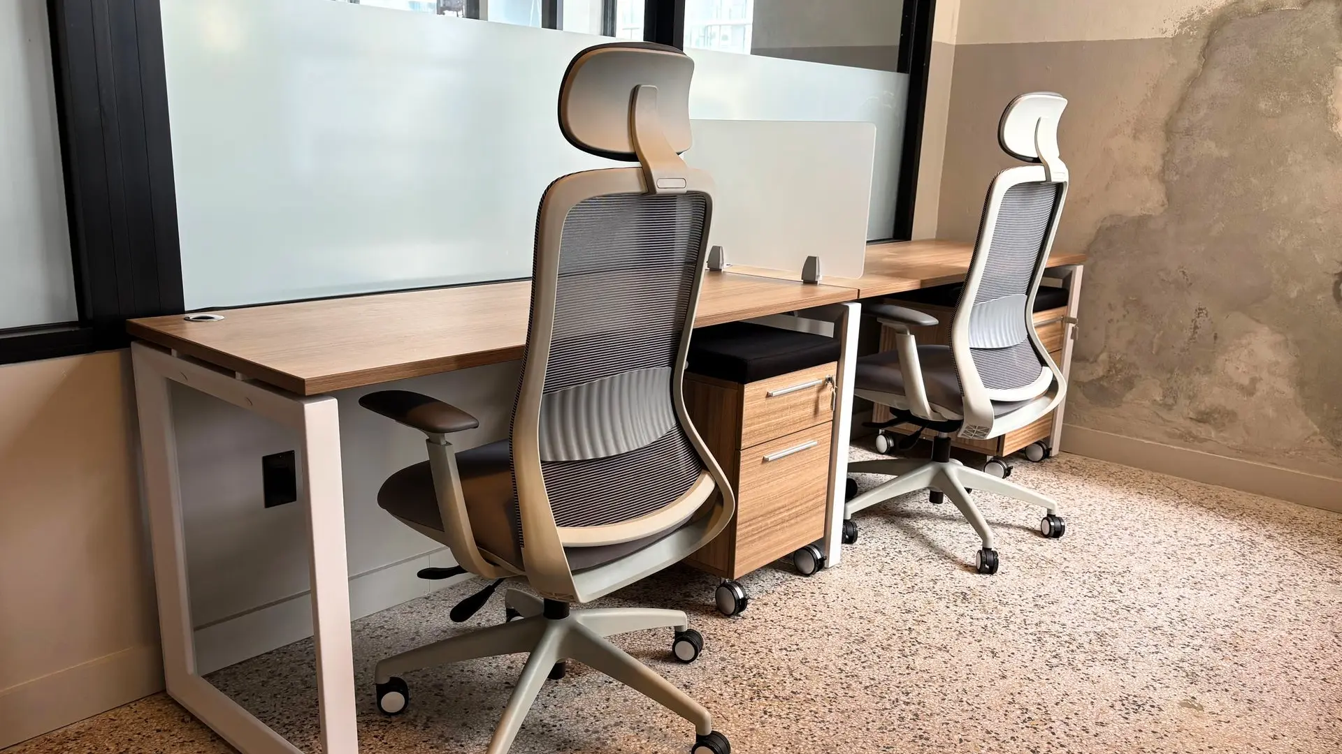 Private office with an L-shaped wood desk and two grey mesh task chairs