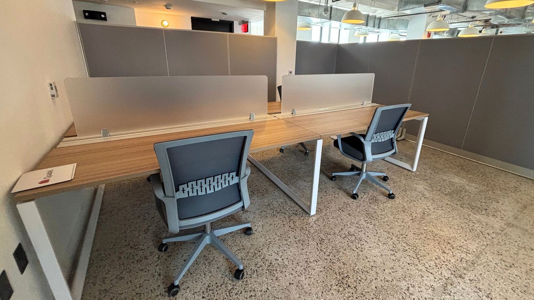 Workstation run with grey privacy screens and grey task chairs on terrazzo flooring