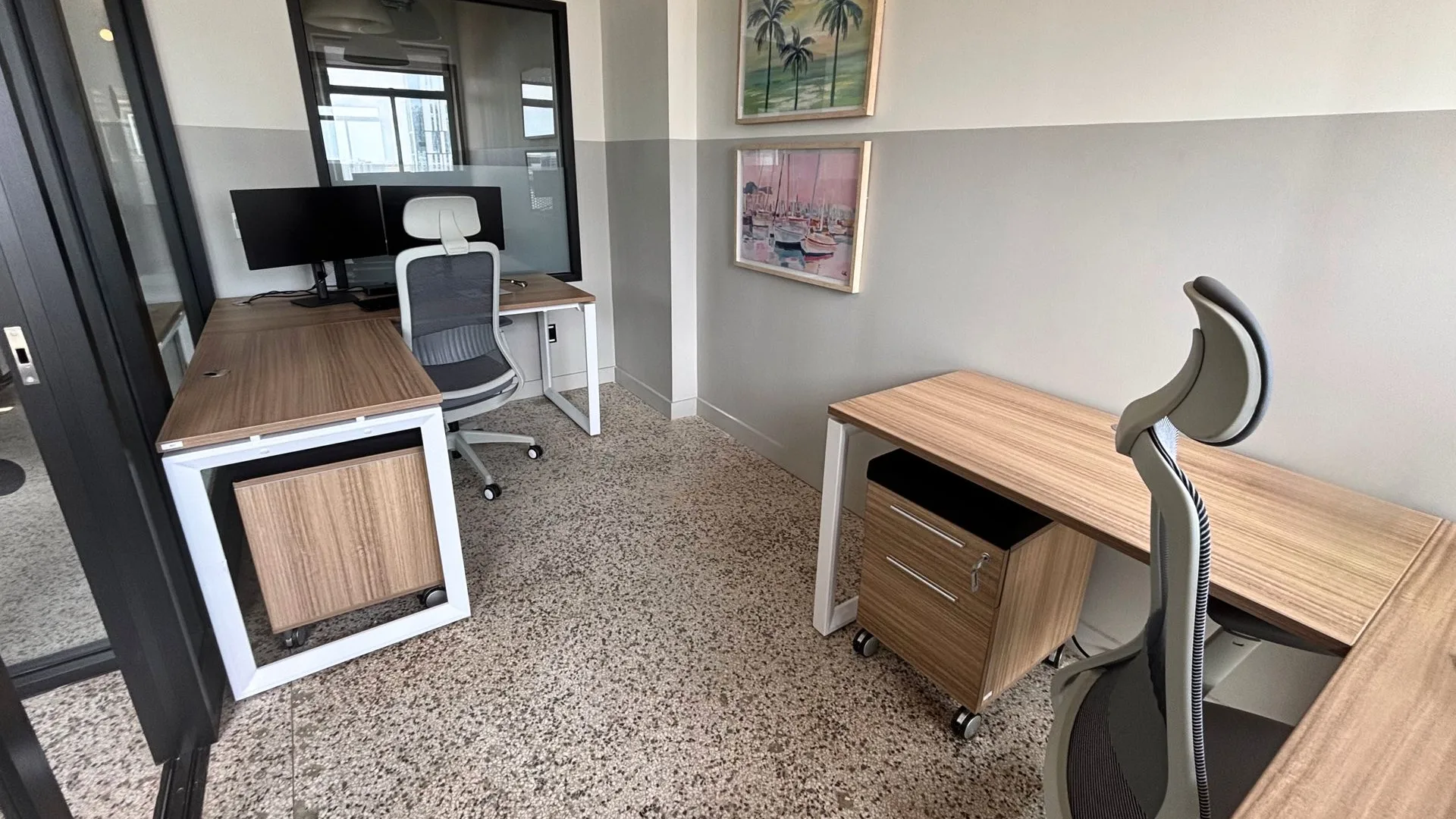 Private office with a wood desk, a grey task chair, framed art and a storage pedestal