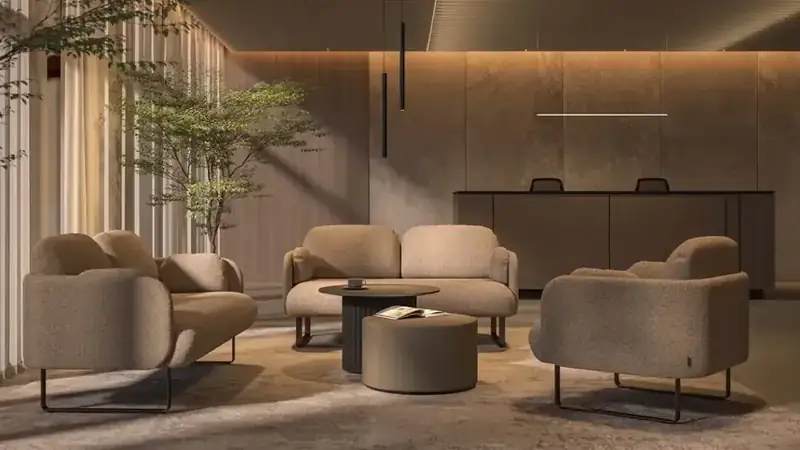 Hotel-style lobby lounge with sofas, an armchair and round tables in front of a reception desk